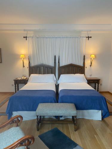 two beds in a bedroom with two chairs and a window at Parador de Vilalba in Villalba