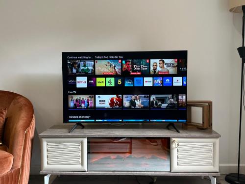 a flat screen tv sitting on top of a tv stand at The Phantom Apartment 1 minute walk to JR, Churchill Manor Nuffield Hospitals Oxford B Uni, Sleeps 5 Guests comfortably very modern 2 rooms 3 bathrooms Private Garden in Oxford