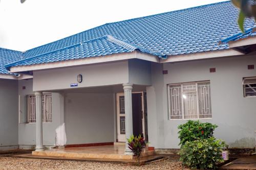 a white house with a blue roof at Kimi's Place Lodge in Mzuzu