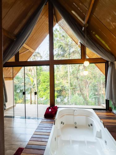 a bath tub in a room with a large window at Pousada Vale das Orquídeas in Lavrinhas