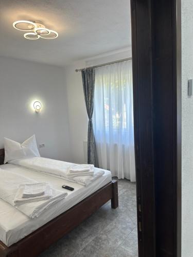a bedroom with a bed with white sheets and a window at Pensiunea Casa Suciu in Cugir