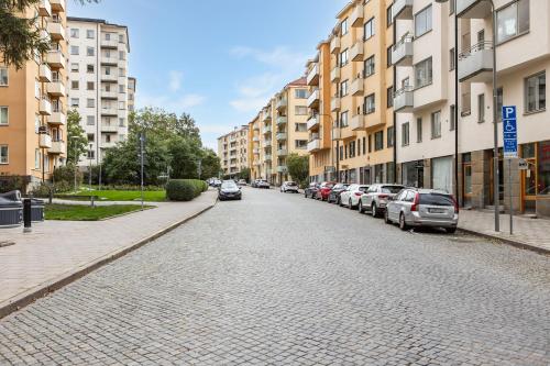 a cobblestone street in a city with parked cars at Trendy & Central Stockholm Apt in Stockholm