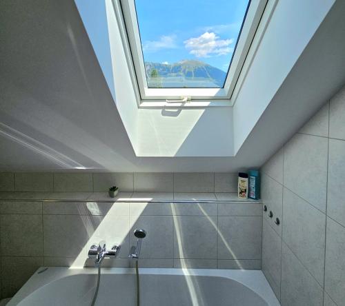 Un tragaluz en un baño con bañera con ventana. en Green Hill Apartments, en Žirovnica