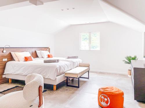a white bedroom with a large bed and a chair at Mogador Beach House, luxury and uniqueness in Grand Case. in Grand Case