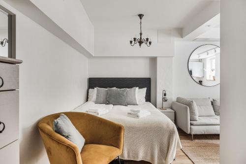 a white bedroom with a bed and a chair at Trendy & Central Stockholm Apt in Stockholm
