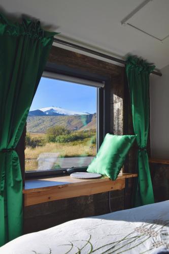 a bedroom with a window with a green curtain at The Holy Ram Farm-Hotel in Snæfellsbær