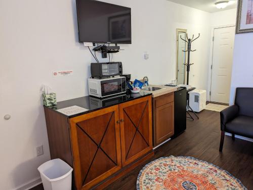a room with a kitchen with a microwave and a tv at Apple Inn and Suites Cooperstown Area in Milford