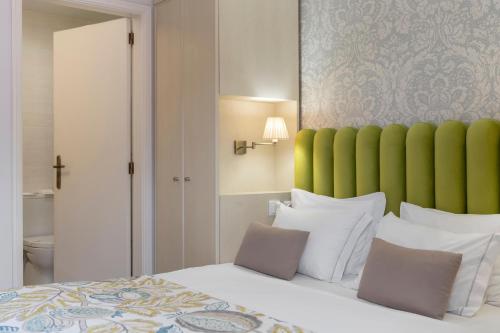 a bedroom with a large bed with a green headboard at Hotel Madeira in Funchal