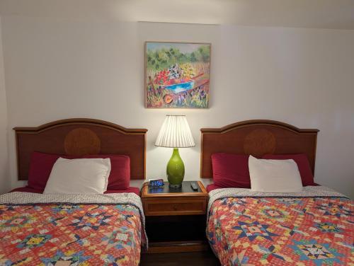 a bedroom with two beds and a table with a lamp at Apple Inn and Suites Cooperstown Area in Milford