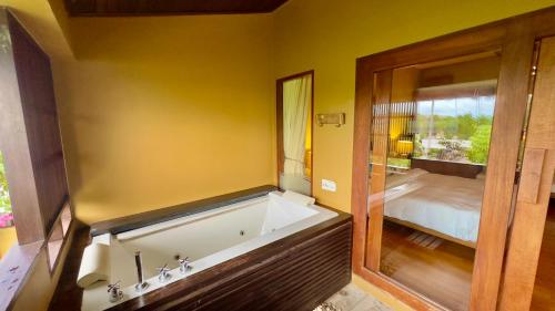 a bath tub in a room with a bedroom at Deva Beach Resort Samui in Choeng Mon Beach