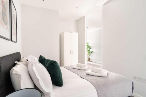 a white bedroom with a bed with green and white pillows at Stylish 2 Bed Apartment in Waterloo Liverpool in Liverpool