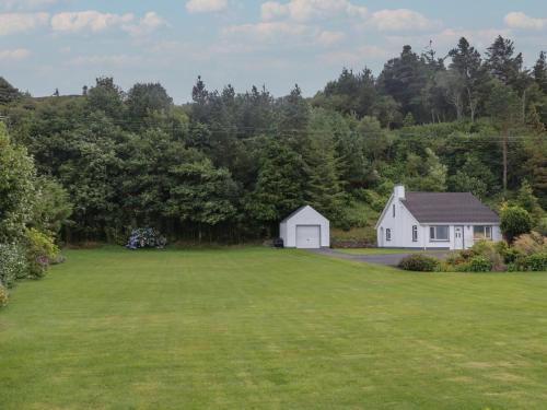 a large yard with a white house in the background at Nelly's Chalet in Gortahork