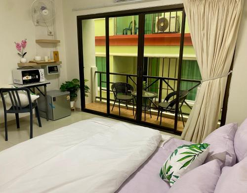 a room with a bed and a balcony with a table at Patong Rest & Recharge in Patong Beach