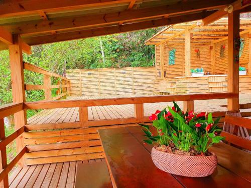 una terraza de madera con un banco y flores. en Casa dos Alpes com Jacuzzi hidro e Lareira, en Santo Amaro da Imperatriz