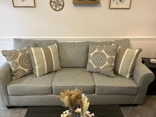 a gray couch with pillows in a living room at Your Weaver Rest Stop on the Ladiga Trail! in Weaver