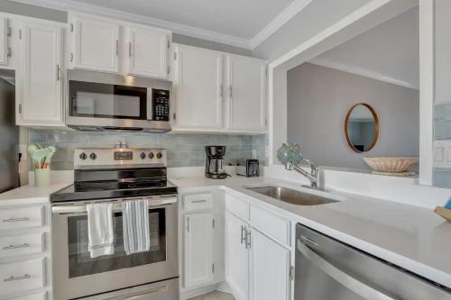 a white kitchen with a stove and a sink at The Salty Breeze - Ocean Front 1 Bedroom in St. Helena Island