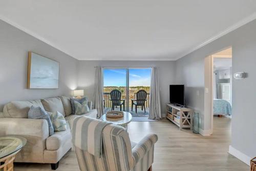 a living room with a couch and a table with chairs at The Salty Breeze - Ocean Front 1 Bedroom in St. Helena Island