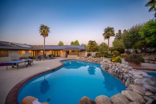a swimming pool with a rock wall around it at Casteel - 4,500 sq-ft retreat with a pool and hot tub in the middle of wine country! in Templeton