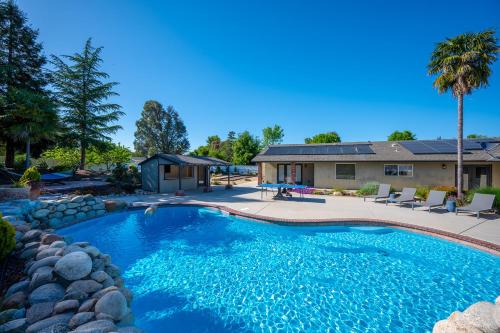 a swimming pool in a yard with chairs and a house at Casteel - 4,500 sq-ft retreat with a pool and hot tub in the middle of wine country! in Templeton