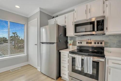 a kitchen with white cabinets and a stainless steel refrigerator at The Salty Breeze - Ocean Front 1 Bedroom in St. Helena Island