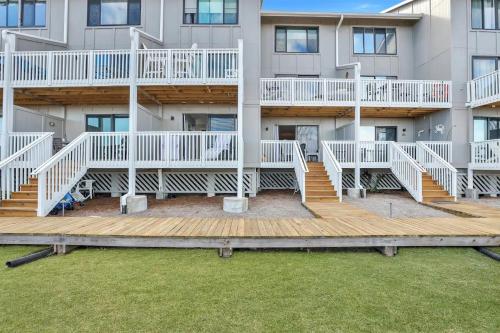 a large building with white balconies and a wooden deck at The Salty Breeze - Ocean Front 1 Bedroom in St. Helena Island