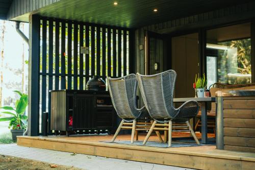 two chairs sitting on a porch with a table at Cocodeno-'Virš Ąžuolų' - Forest SPA - FREE jacuzzi in Paplatelė