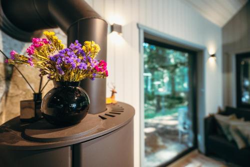 a table with a vase with flowers on it at Cocodeno-'Virš Ąžuolų' - Forest SPA - FREE jacuzzi in Paplatelė