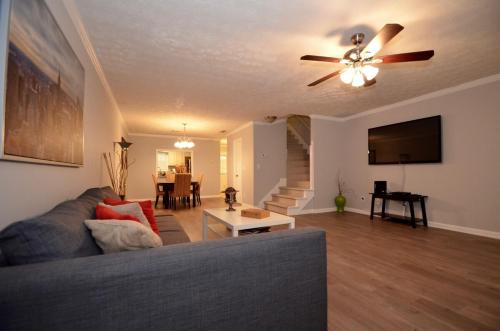 un soggiorno con un divano e un ventilatore a soffitto di The Cozy Pearl Townhome - 10 mins to horse park a Conyers