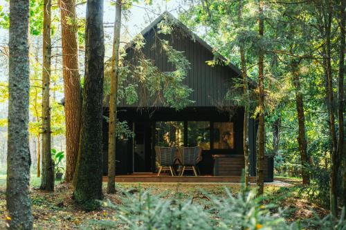 a house in the woods with a deck and chairs at Cocodeno-'Virš Ąžuolų' - Forest SPA - FREE jacuzzi in Paplatelė