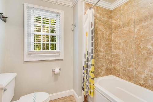 a white bathroom with a tub and a toilet at Private Pool Spacious 5BR Family-Friendly Home in Conyers