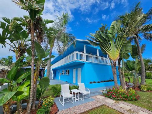 a blue house with palm trees and chairs at Seaside Cove in Fort Pierce
