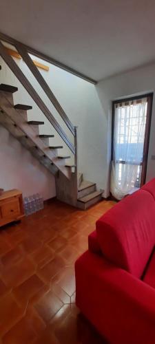 a living room with a red couch and stairs at Le Chat Riant Deluxe in Fenis