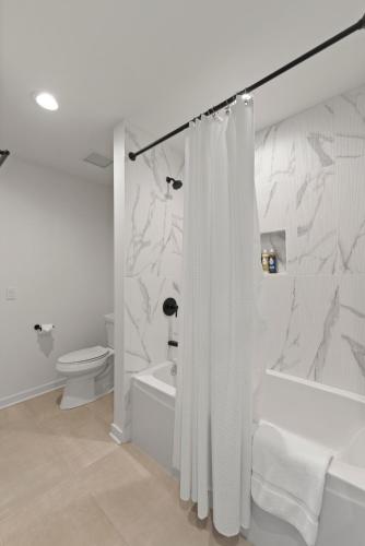 a white bathroom with a shower curtain and a toilet at K2 Sky High Apartments with Stunning Chicago Views in West Loop in Chicago