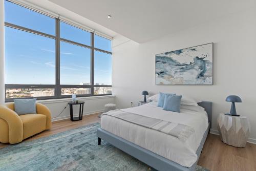 a bedroom with a bed and a chair and windows at K2 Sky High Apartments with Stunning Chicago Views in West Loop in Chicago