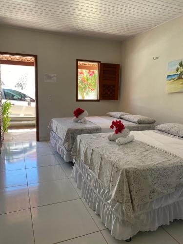 three beds in a room with red flowers on them at Pousada Caminho do Paraíso in Jijoca de Jericoacoara