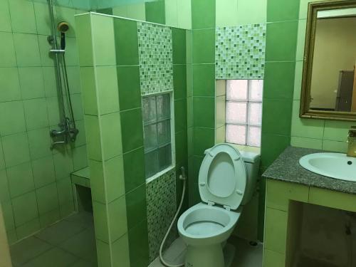 a green bathroom with a toilet and a sink at Gold house apartment in Vientiane