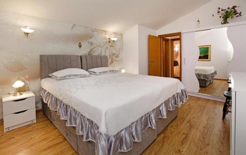 a bedroom with a large bed with white sheets and wooden floors at Villa Goga in Vela Luka