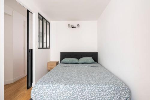 une chambre avec un lit dans une pièce blanche dans l'établissement Apt moderne rénové et spacieux, au cœur de Paris, à Paris