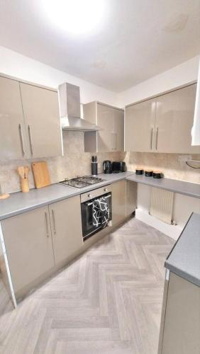 a kitchen with white cabinets and a stove top oven at Cozy 4-Bed House in Accrington in Accrington
