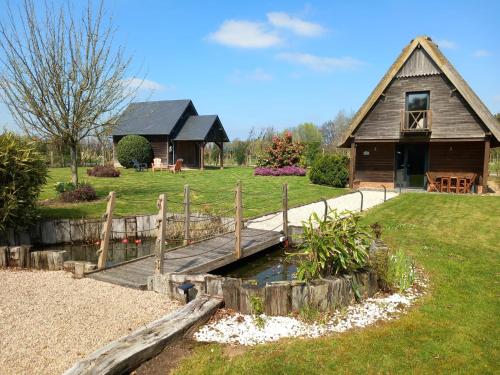 een houten brug over een vijver voor een huis bij Cottage du Becquet in Épaignes