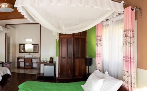a bedroom with a bed and a window with curtains at Andasibe Lemurs Lodge in Andasibe