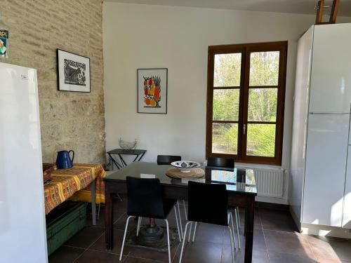 una stanza con un tavolo, delle sedie e una finestra di Magnifique Moulin proche Chablis, jacuzzi et rivière a Annay-sur-Serein