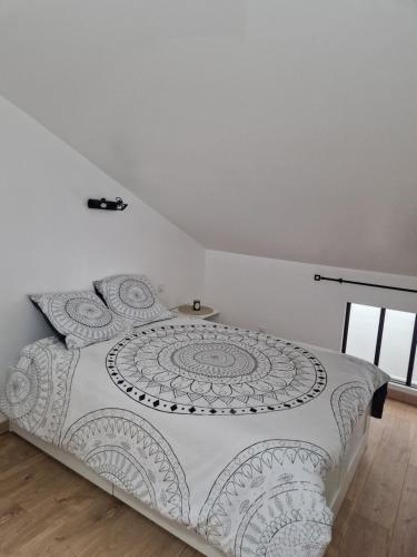 a white bed with a black and white comforter at La Forge in Parmilieu