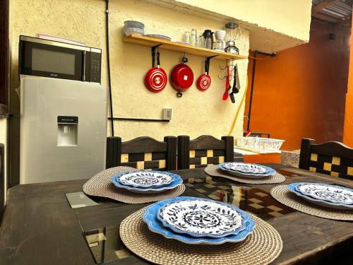 圣克里斯托瓦尔-德拉斯卡萨斯Casa Faro的一张木桌，上面放着四个盘子和一个冰箱