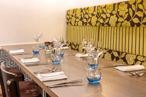a long table with glasses and napkins and a couch at Georgian House Hotel in Whitehaven