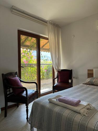 a bedroom with a bed and two chairs and a window at Villa hira in Eski Datca