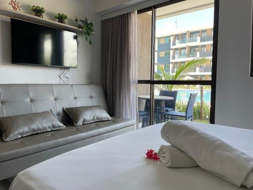 a bedroom with a bed and a couch and a television at Makia Beach Experience Muro Alto Porto de Galinhas in Ipojuca