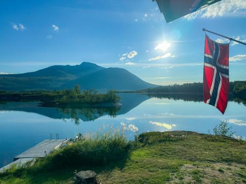 a view of a lake with a flag on a dock at Fairytale STAYcation - JACUZZI, BOAT & SAUNA in Bjørkli