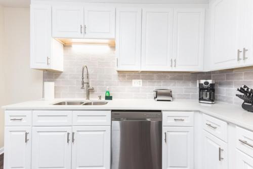 a kitchen with white cabinets and a stainless steel dishwasher at The Modern Serenity Townhome -10 mins to Horsepark in Conyers