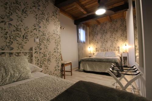 a bedroom with two beds and floral wallpaper at Apartamentos Vedelejos in Hervás